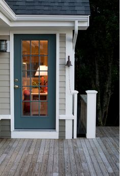 a blue front door on a white house with wood flooring and wooden decking