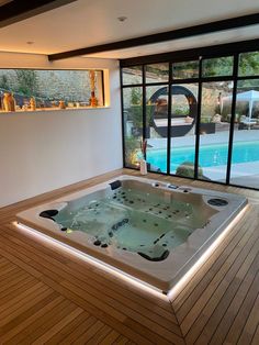 an indoor jacuzzi tub in the middle of a wooden floored room with large windows