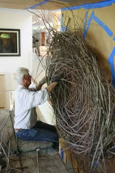 a man working on a sculpture made out of twigs