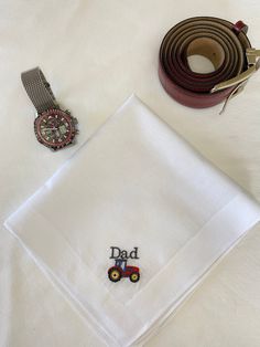 "Embroidered handkerchief with a \"tractor\" Fathers day motif The word \"DAD\" may be changed to a name if you wish to personalise the handkerchief.  These quality handkerchiefs are made from the softest cotton.  Size: 40x40cm (e)  Excellently crafted from 100% premium COTTON.  This comes in a beautiful gift envelope closed with a satin ribbon. The hankies are made to order. Lovely to have. stylish enough for daily use or as a special Fathers Day gift" Classic Handkerchiefs For Father's Day Gift, Classic Cotton Handkerchiefs As Gift, Embroidered Cotton Handkerchiefs As Gifts, Cotton Handkerchief With Machine Embroidery For Gift, Personalized Cotton Handkerchiefs, Embroidered Handkerchief, Gift Envelope, Satin Ribbon, Gift For Him