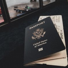 three passport cards stacked on top of each other in front of a window with an american flag