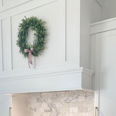 a wreath is hanging on the wall above an oven hood in a kitchen with marble counter tops