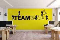 an office with two desks and a yellow wall that says teamwork on it