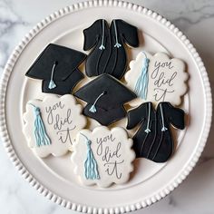 cookies decorated with graduation caps and tassels are on a white plate that says you did it