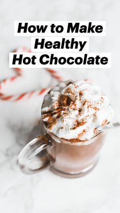 hot chocolate drink with whipped cream and candy cane on white marble background, top view