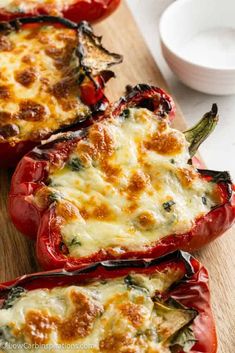 three stuffed red peppers on a cutting board