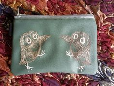 an owl purse with two small owls on it's front and one is green