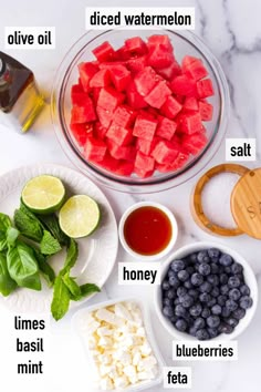 the ingredients for watermelon salad laid out on a marble counter top with limes and blueberries