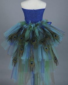 a mannequin dressed in blue and green with peacock feathers on it's skirt