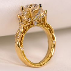 a close up view of a yellow gold ring with diamonds on the band and side stones