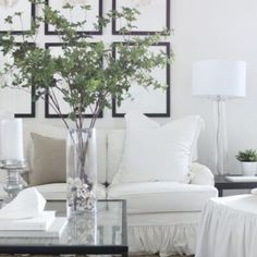 a living room filled with white furniture and pictures on the wall above it's coffee table