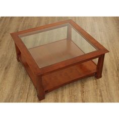 a glass top coffee table with wooden legs on a wood flooring area in an empty room