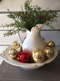 a white vase filled with gold and red ornaments