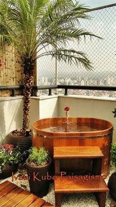 a hot tub sitting on top of a wooden deck next to potted plants and trees