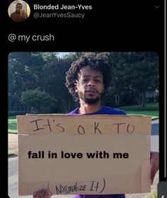 a man holding a sign that says it's ok to fall in love with me