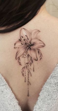 the back of a woman's neck with a flower tattoo