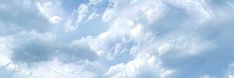 a man flying a kite on top of a lush green field under a cloudy blue sky