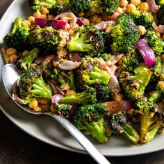 a white plate topped with broccoli and chickpeas next to a fork