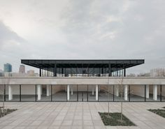 an empty courtyard in front of a large building with columns and trees on the ground