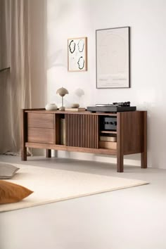 an entertainment center in a living room with white carpet and artwork on the wall behind it