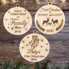 three personalized christmas ornament hanging on a wooden background with pine branches and lights