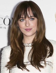 a woman with long brown hair and blue eyes wearing a white dress at an event