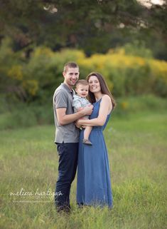 a man and woman holding a baby in a field