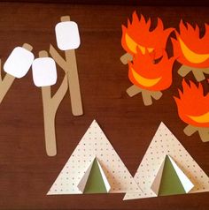 paper cut out of trees and campfires on a wooden table with other items