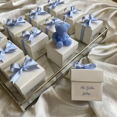 there are many small boxes that have blue bows on them and one has a teddy bear in the middle