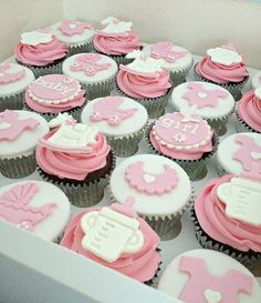 cupcakes with pink and white frosting are arranged in a box on the table