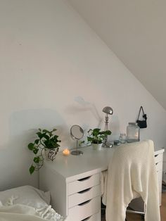 a bedroom with white furniture and plants on the desk