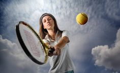 a woman holding a tennis racquet on top of a tennis ball in the air