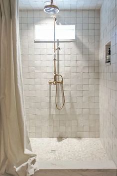 a bathroom with a shower and white tiled walls, along with a curtained window