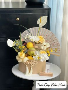 a table topped with a cake covered in flowers and fruit next to a black dresser