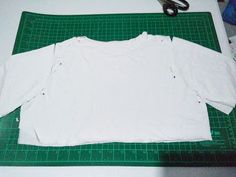 a white shirt is laying on a green cutting mat