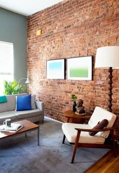 a living room filled with furniture and a brick wall