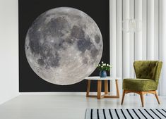 a living room with a large full moon on the wall next to a green chair