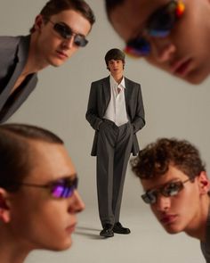 three men in suits and sunglasses are looking at each other while one man is standing behind them