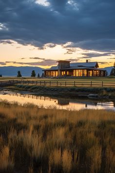 a large house sitting on top of a lush green field next to a body of water