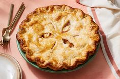 a pie sitting on top of a green plate next to silverware and utensils