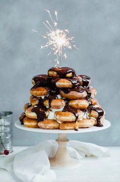 a stack of doughnuts on a cake stand with a sparkler in the background