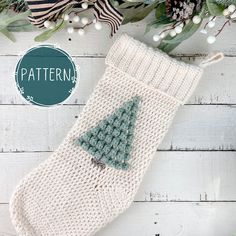 a knitted christmas stocking with a green tree on it and white berries around it