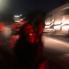 a blurry photo of two people walking down the street at night with lights in the background