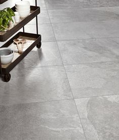 a grey tile floor with two trays holding plants and bowls on it's sides