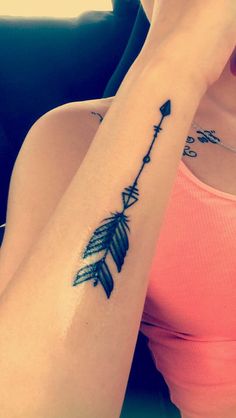 a woman's arm with an arrow tattoo on the left side of her arm