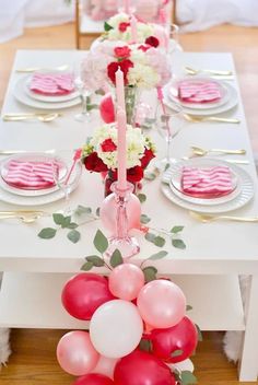 the table is set with balloons, plates and silverware for an elegant valentine's day celebration