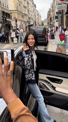 a woman standing in the back of a car waving at someone with her hand up