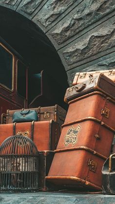 several pieces of luggage sitting next to each other in front of a stone tunnel with a birdcage