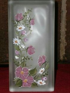 a glass plate with pink and white flowers painted on the side, in front of a brick wall