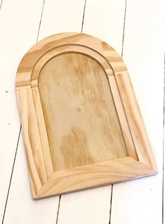 an oval wooden frame on a white wood floor with the edge cut out to look like it has been carved